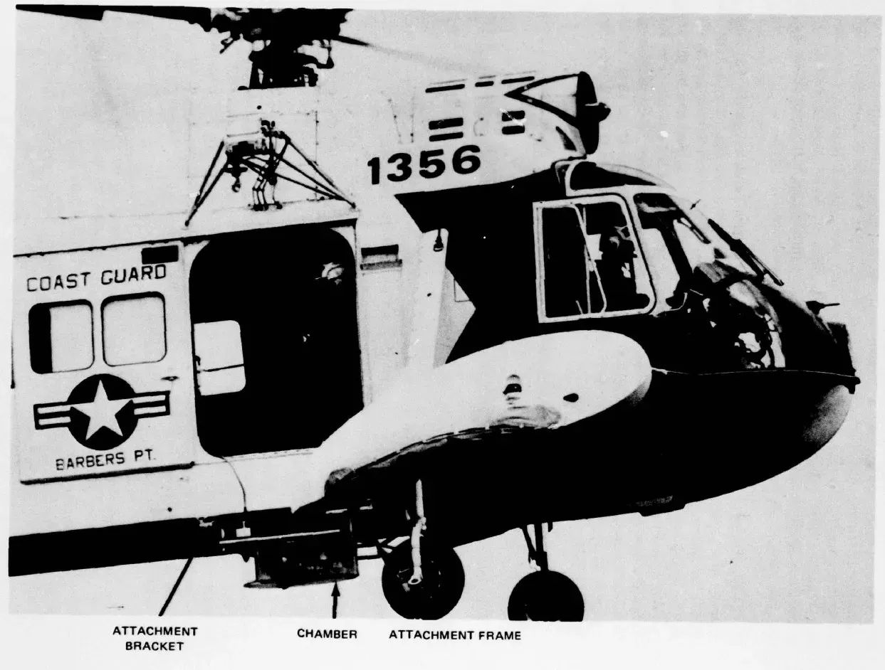 Coast-Guard-Helikopter 1356 aus Barbers Point mit der Anbringung der Tauben-Kammer unter dem Rumpf, beschriftet mit Attachment Bracket, Chamber und Attachment Frame.